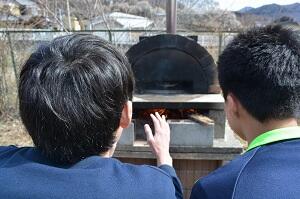 ピザ窯をのぞく生徒